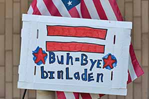 An American flag and homemade sign reading Buh-Bye-bin-Laden
