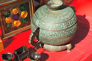 An ancient green ceramic Chinese pot with metallic cups on display at the International Featival