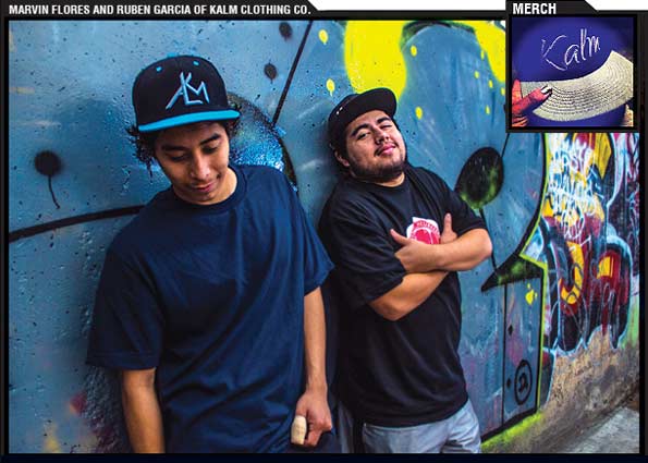 Marvin Flores and Ruben Garcia, both wearing caps by their KALM Clothing Company, stand against a wall with colorful murial. At the corner is a blue cap with white weaving pattern on the beak and Kalm logo on the front.